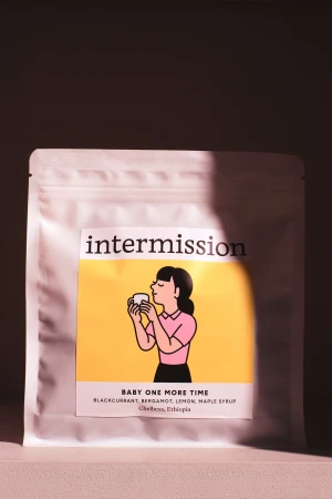Sealed package of Intermission brand coffee, featuring an illustrated woman enjoying a cup against a yellow background.