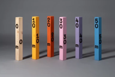 Six vertical wooden blocks marked with numbers and the letter m stand in a row against a grey seamless background.