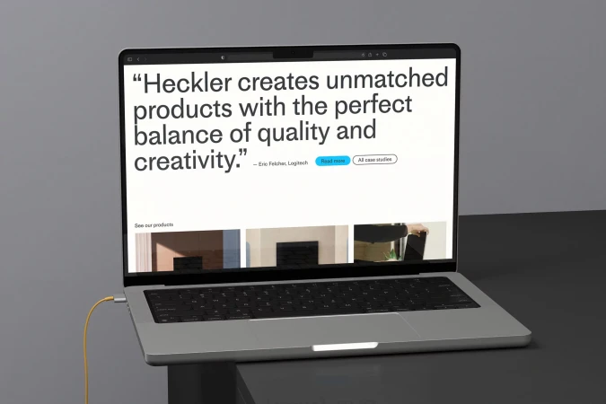 Silver laptop on a dark surface displays a website with a quote and product images, connected by a yellow cable.