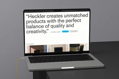 Laptop computer displaying website on a dark desk against a plain grey wall background