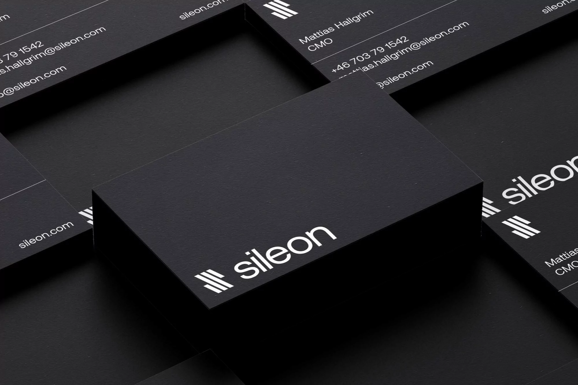 Close-up of black business cards with the 'sileon' logo and contact information arranged against a solid black background.