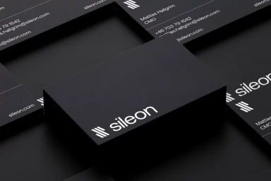 Close-up of matte black business cards with white Sileon branding and contact information arranged on dark surface