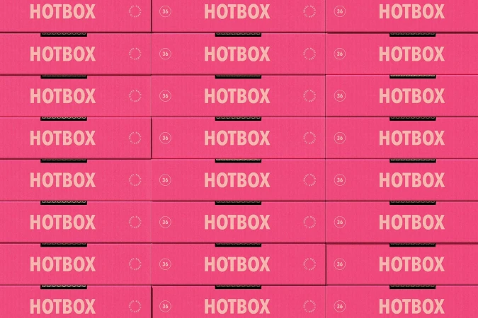 Stacks of pink Hotbox branded cardboard boxes, arranged in rows. The boxes appear to be unopened and new, ready for shipping.