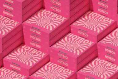 Stacked vibrant pink pizza boxes featuring a cream-colored hypnotic spiral pattern and Hotbox typography.