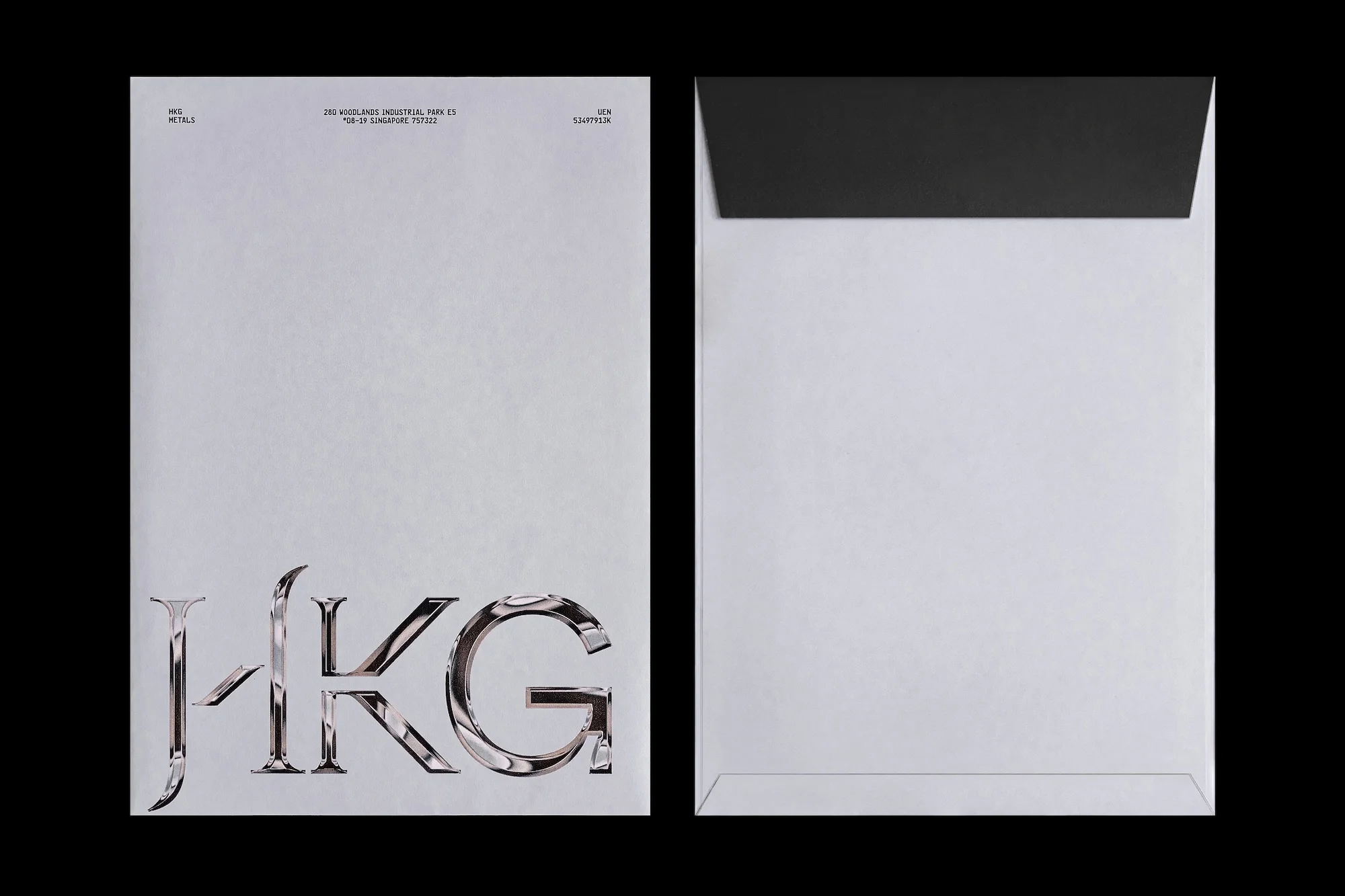Two white envelopes, one with a black interior, one with large chrome letters HKG, on a black background, graphic design.