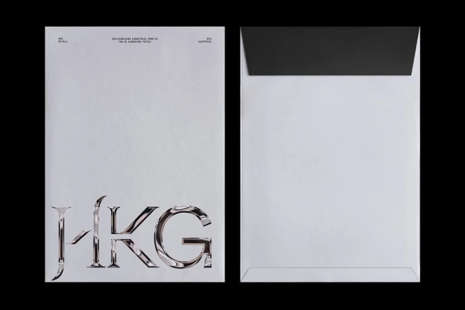 Two white envelopes, one with a black interior, one with large chrome letters HKG, on a black background, graphic design.