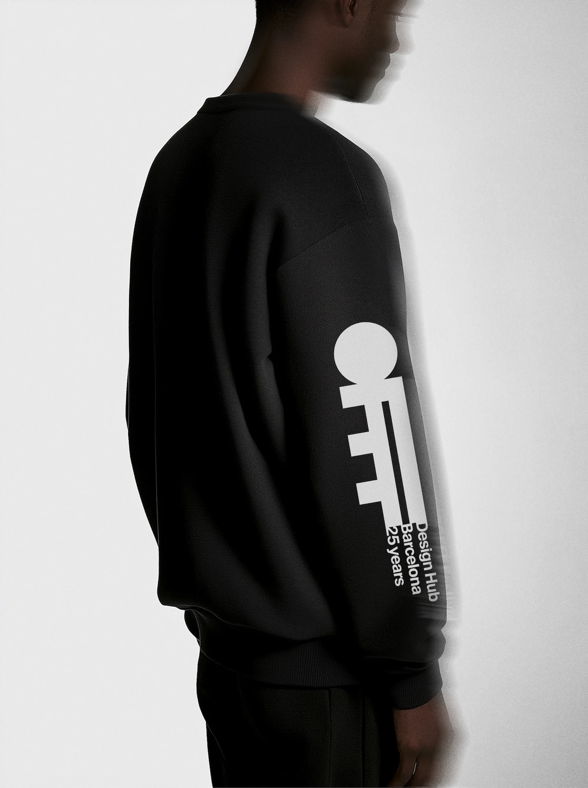 An adult male is partially visible, wearing a black long-sleeve shirt with a white graphic design on the sleeve, against a light background.