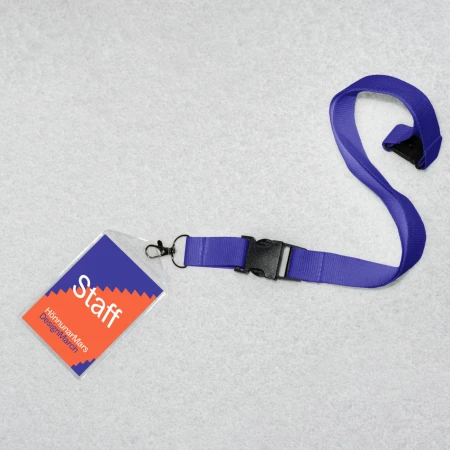 Staff ID badge with purple lanyard and a black buckle on a grey surface, showing the company name and role.