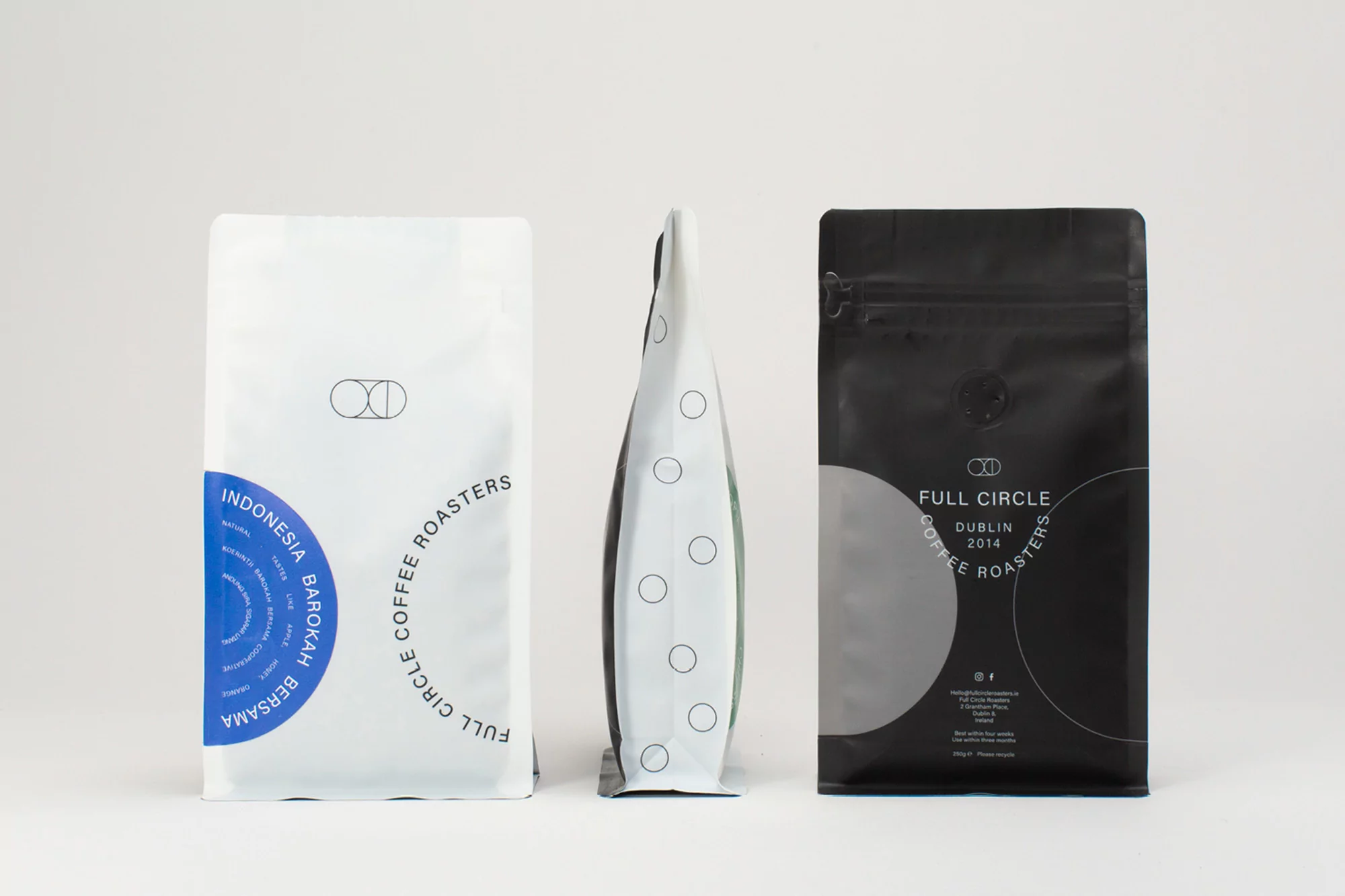 Three sealed bags of Full Circle brand coffee beans, featuring white and black packaging with logo design, arranged on a white surface.