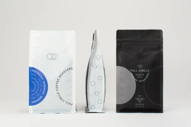 Three coffee bags displayed against a white background, featuring a white bag, a side profile, and a black bag.