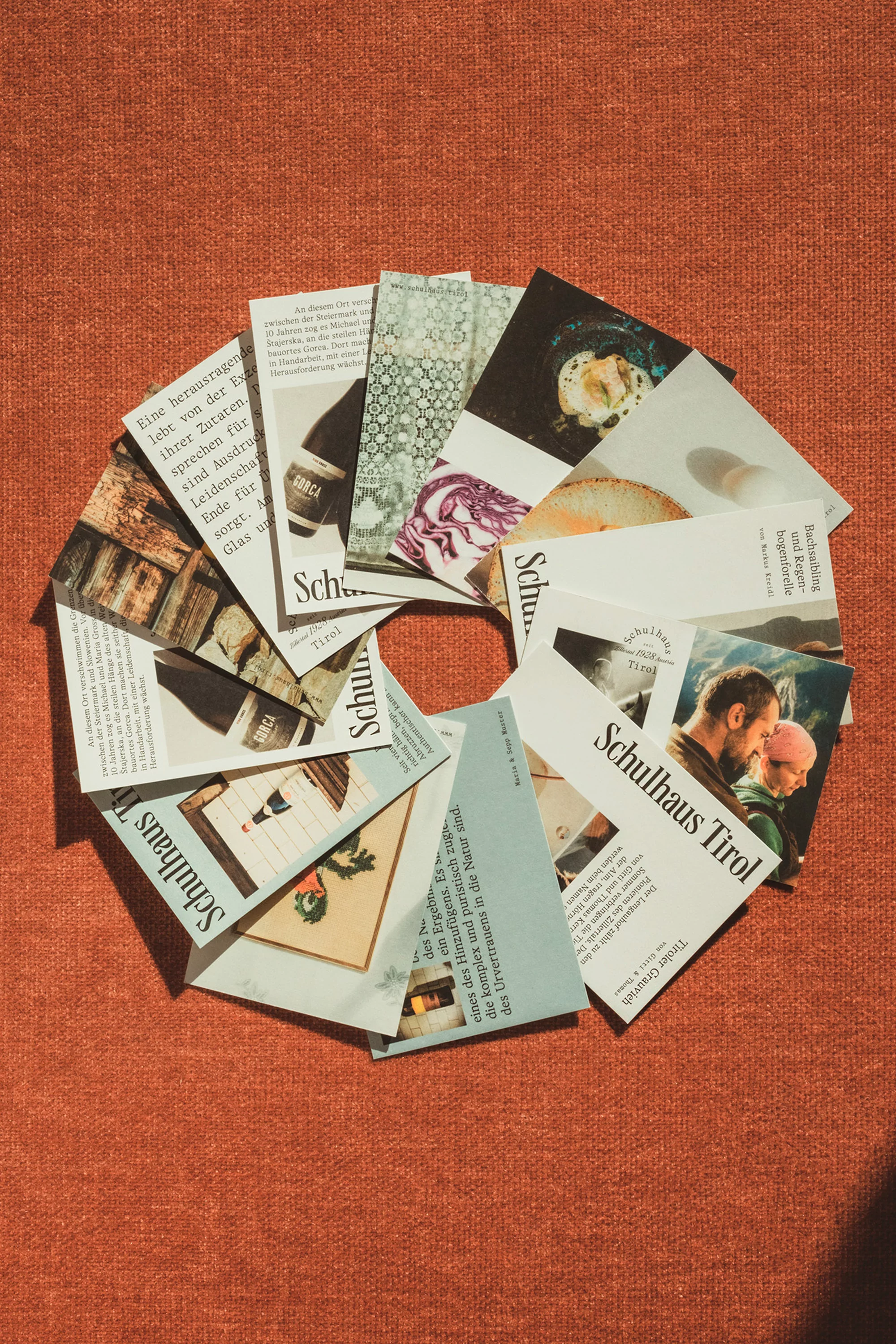 Overhead shot of paper materials arranged in a circular pattern on textured surface, featuring text and image clippings.