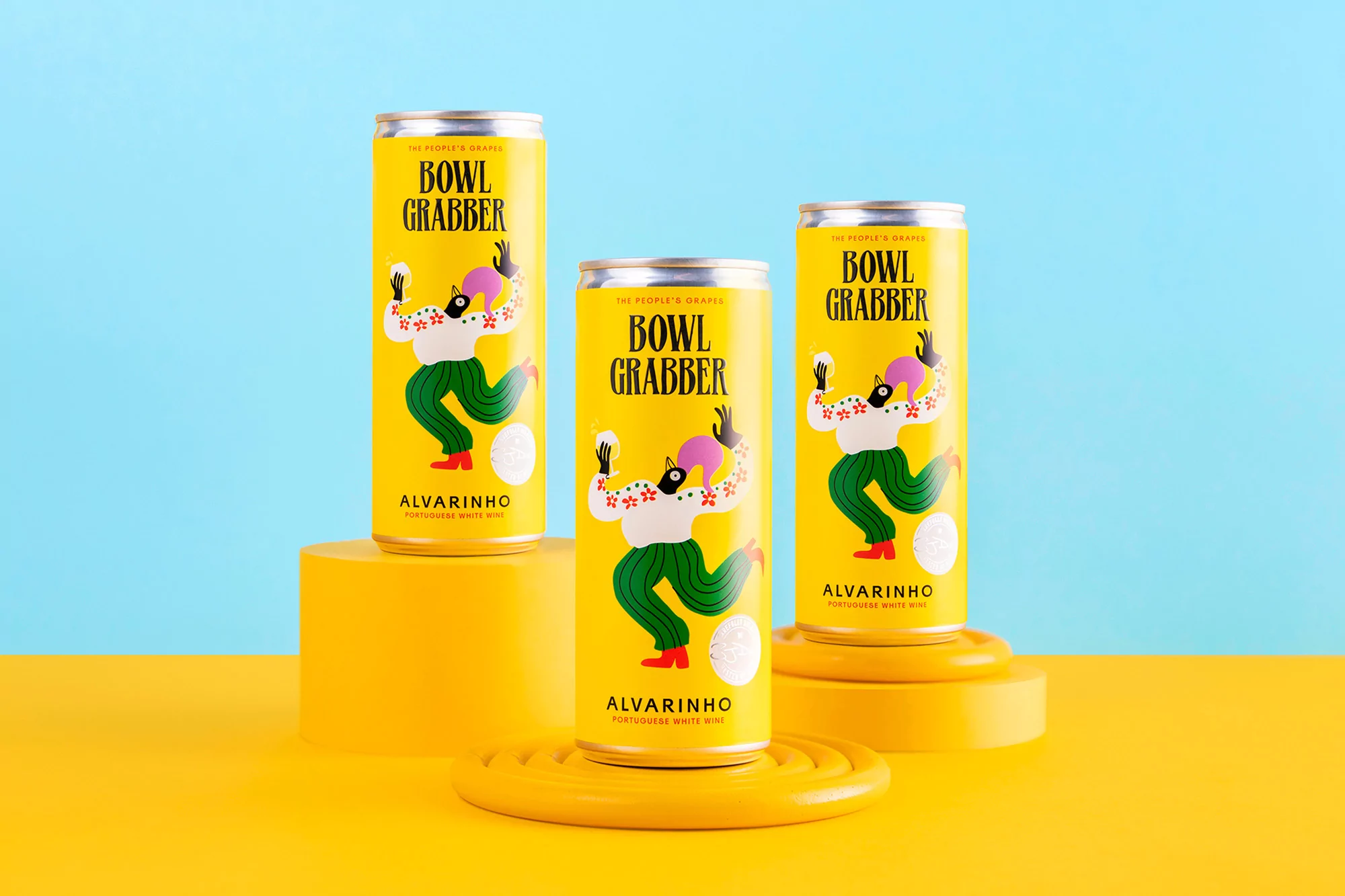 Three yellow cans of Alvarinho Portuguese white wine stand on yellow platforms against a split yellow and blue background, showcasing its packaging design.
