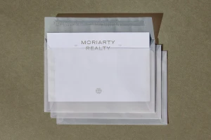 Stacked translucent envelopes holding branded stationery against a textured brown background.