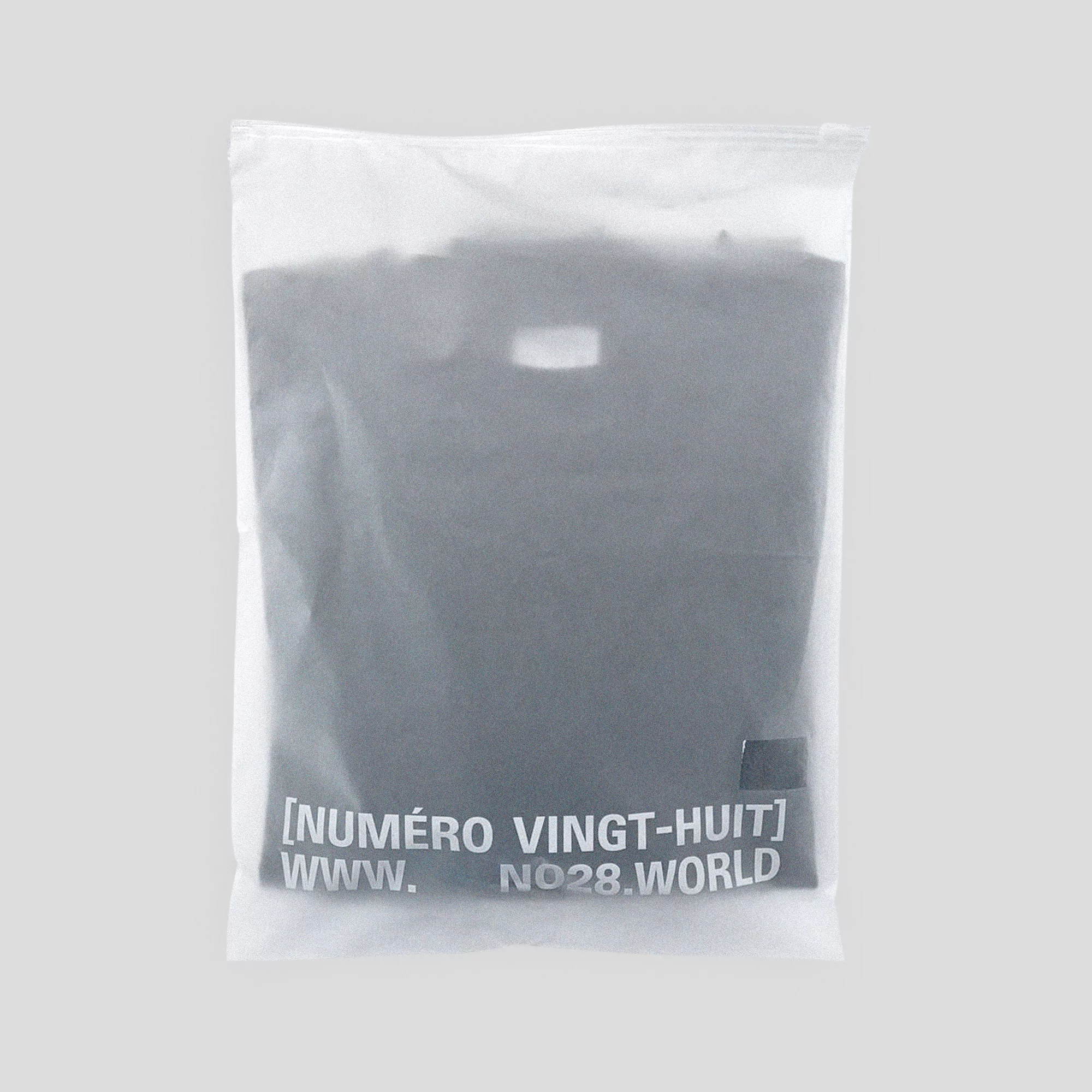 Wrapped black t-shirt in a translucent plastic bag with white printed text on a light grey background.
