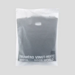 Frosted plastic garment bag containing folded dark apparel with printed white brand text against a light grey background.