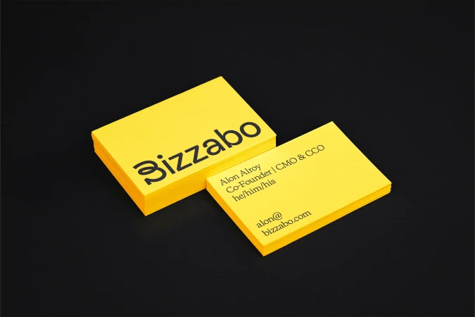 Stack of bright yellow business cards with black text and logo on a dark black background create a modern, minimalist design.
