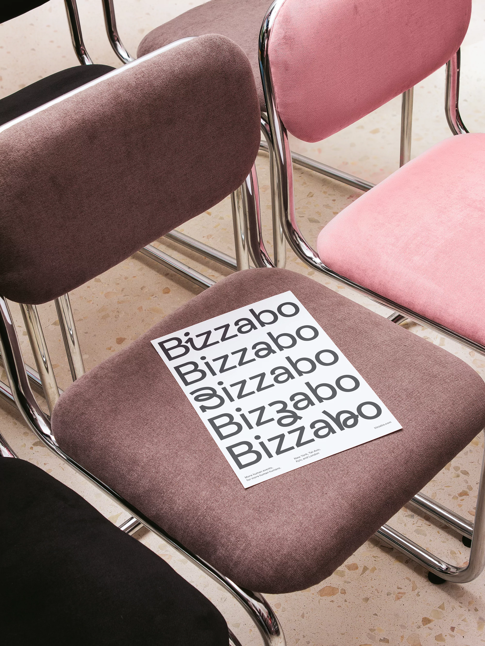 Eye-level shot of multi-colored chairs featuring Bizzabo flyers on the brown chair in a neutral-toned interior setting.