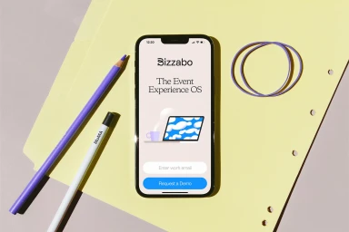 A smartphone displaying the Bizzabo app on a yellow folder beside purple pencils and rubber bands under bright lighting.