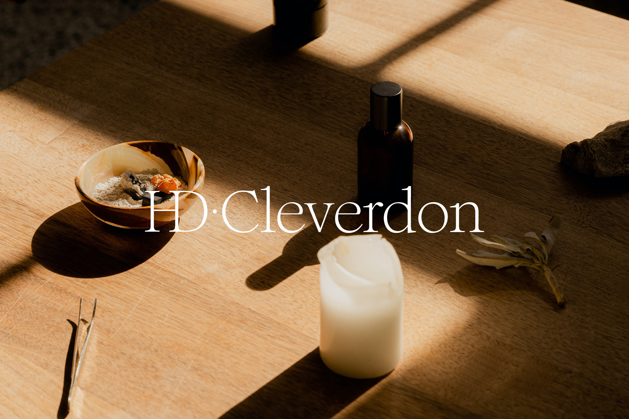 Elevated view of a wooden table displaying an arrangement of toiletries and small objects under natural light, minimalist composition.