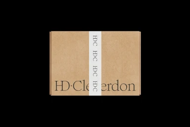 Cardboard shipping box with a white belly band and dark serif typography against a solid black background.
