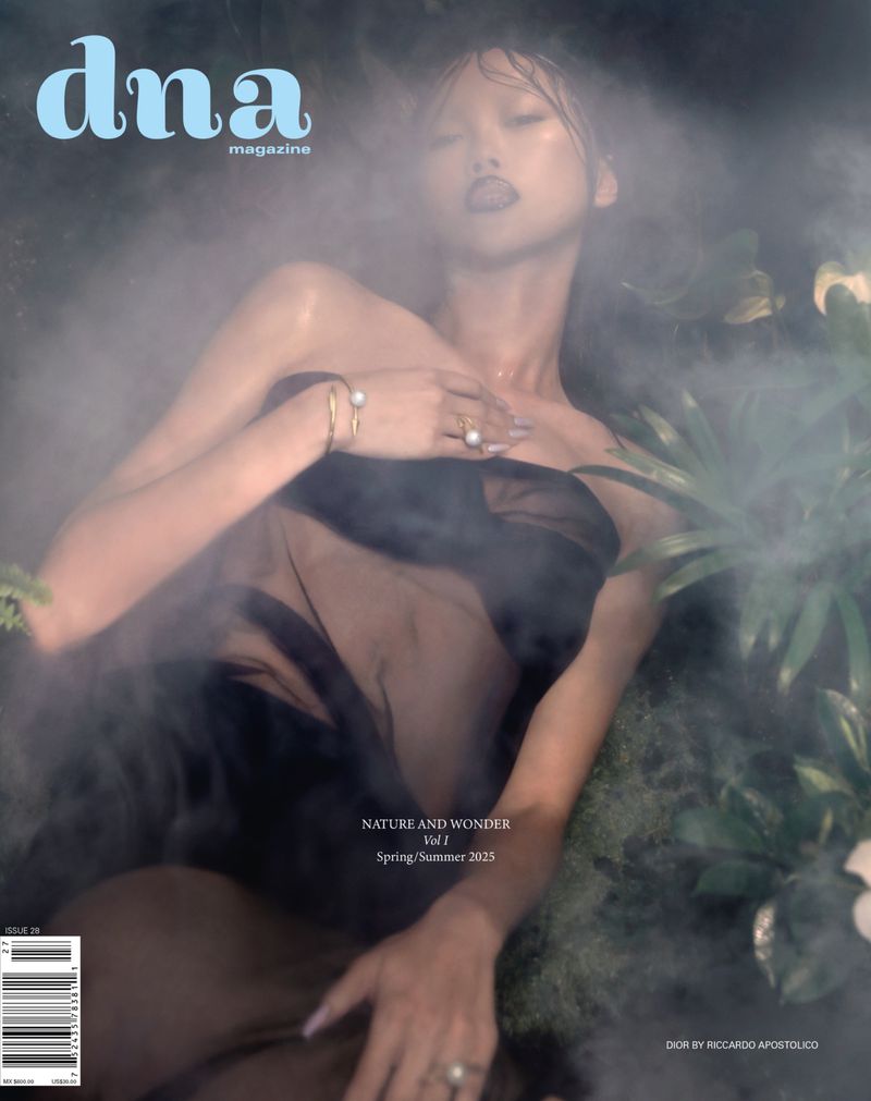 Magazine cover featuring a woman with styled hair and elegant jewelry, surrounded by soft lighting and lush green foliage accents.