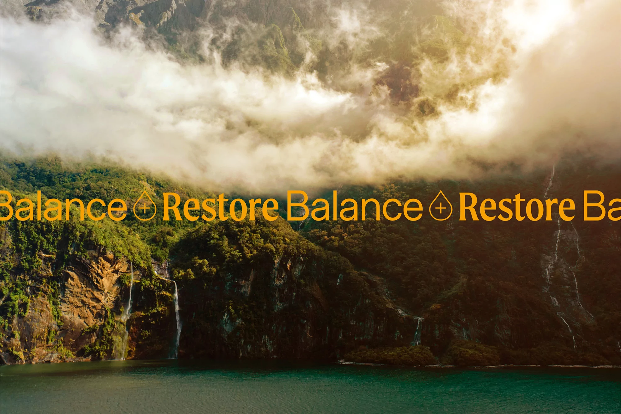 Dramatic mountain vista with low clouds and green lake, waterfall. 'Balance & Restore' text overlay. Nature, beauty, tranquility.