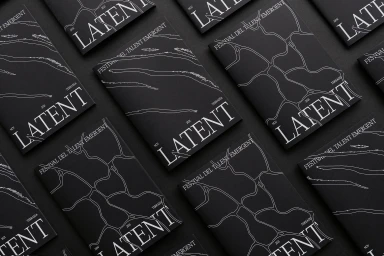 Top-down view of multiple black printed booklets with white typography and abstract line patterns arranged neatly on a dark surface.