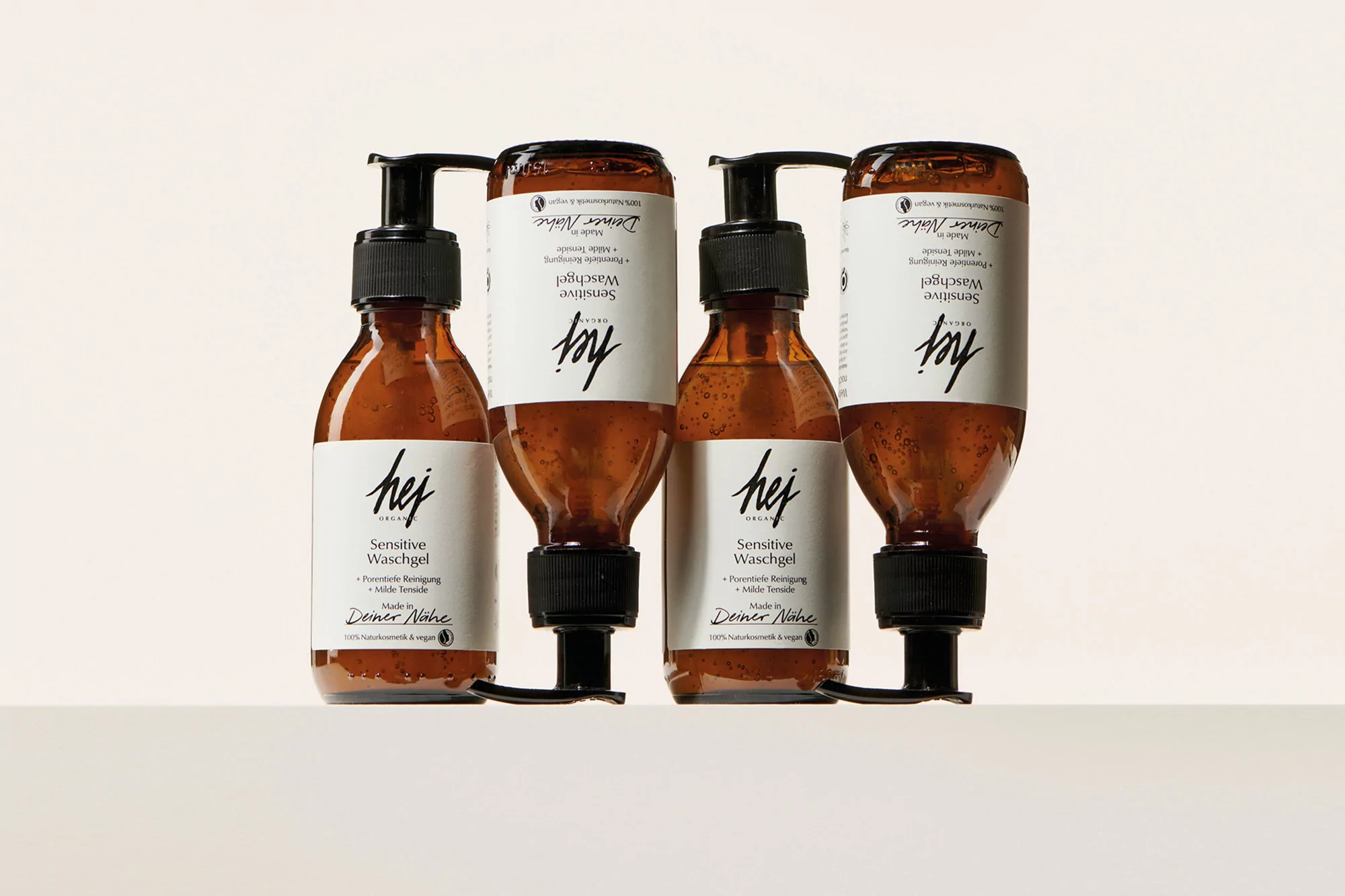 Four identical brown glass bottles of Hej Sensitive Waschgel (face and body wash) sit in a row on a white surface, studio product shot.