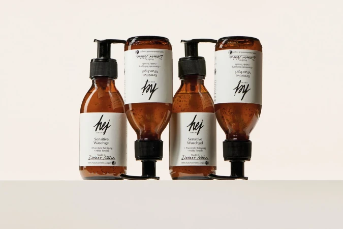 Four identical brown glass bottles of Hej Sensitive Waschgel (face and body wash) sit in a row on a white surface, studio product shot.