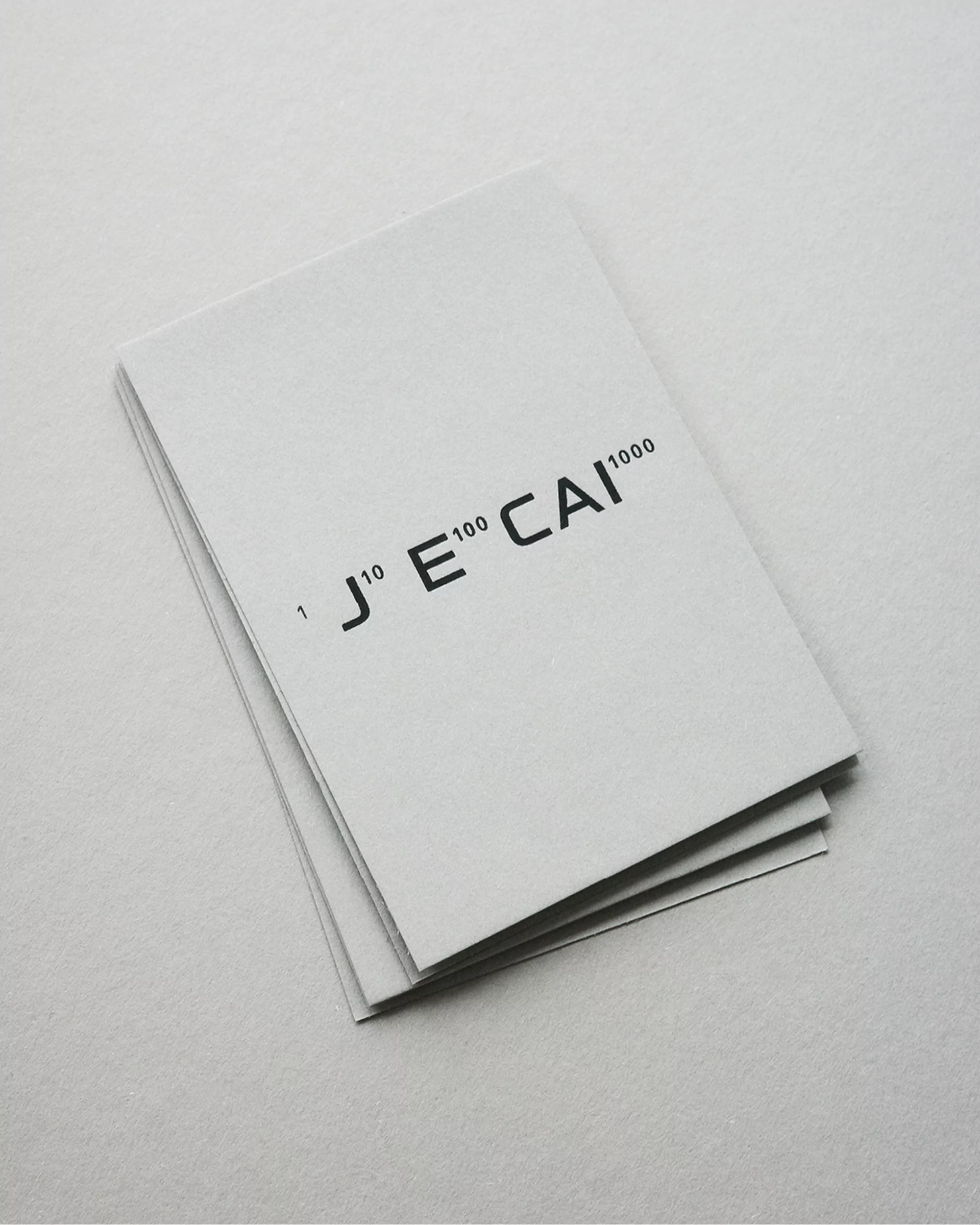 Stack of white booklets with black typography, simple design, clean aesthetic, and minimalist presentation against a light grey backdrop.