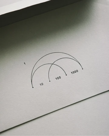 Graphic art print features black semi-circles intersecting with numerical labels on a textured off-white paper backdrop.