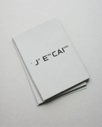 A stack of light grey business cards featuring minimalist black typography with superscript numbers for J E CAI brand identity.