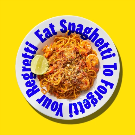 Overhead shot of shrimp scampi pasta dish on white plate with blue text against a bright yellow background, food presentation.