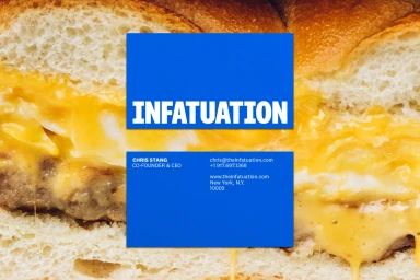 Close up of a breakfast sandwich with melted cheese overlaid with a vibrant blue brand identity card for The Infatuation