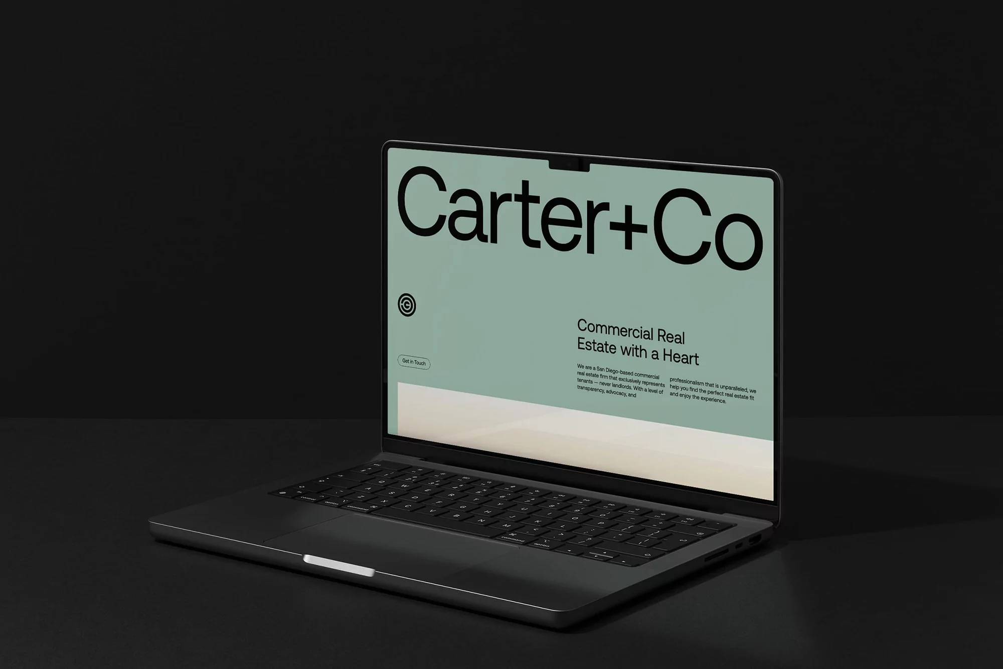 Sleek laptop displays 'Carter+Co' website on sage green screen against a dark backdrop, showcasing modern digital workspace aesthetics.