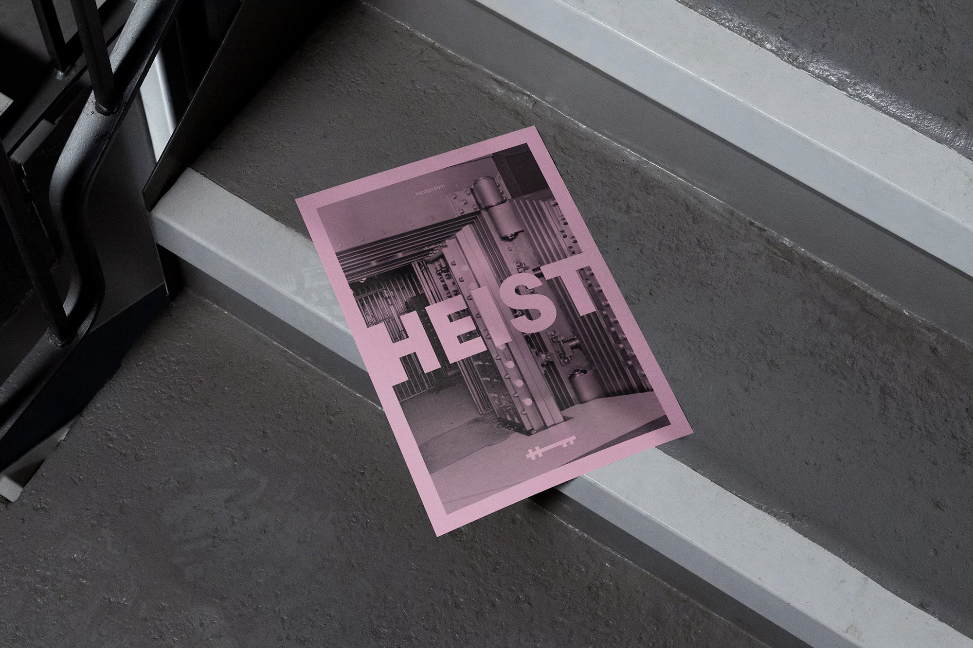 Promotional poster for 'Heist' featuring a bank vault door, placed on gray concrete steps with black metal railings. The poster is pink.