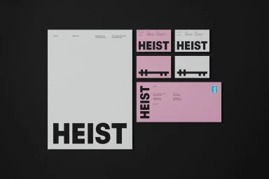 Branding mockup for Heist showing letterhead, business cards, and an envelope featuring bold typography on white and pink paper.