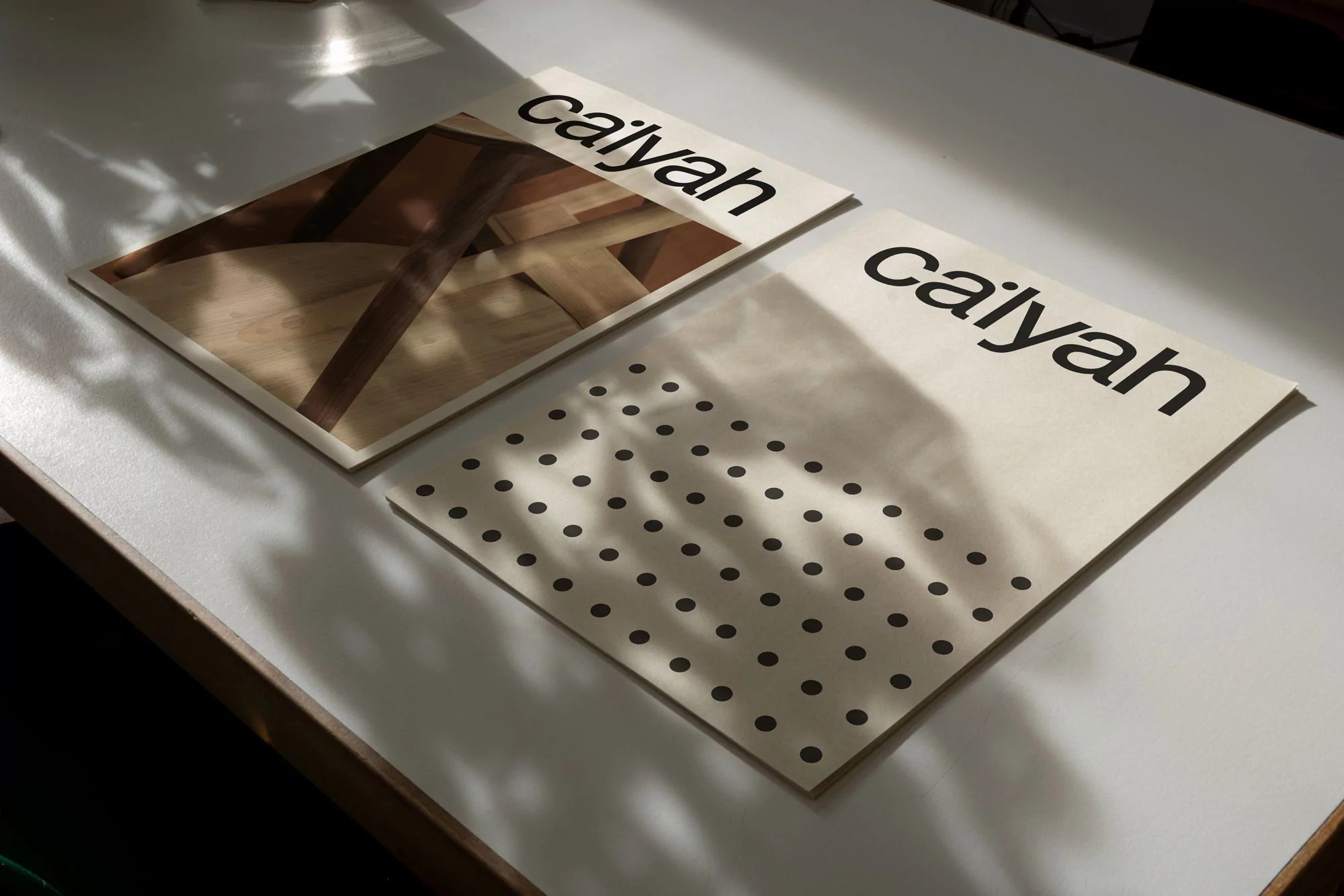 Two printed brand identity posters for Ca'lyah resting on a white table under soft shadows