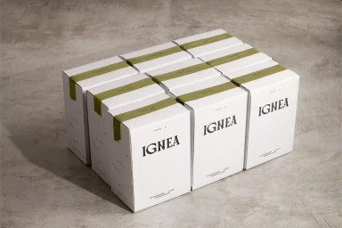 A neat grid of white branded packaging boxes sealed with olive green tape resting on a textured concrete surface.