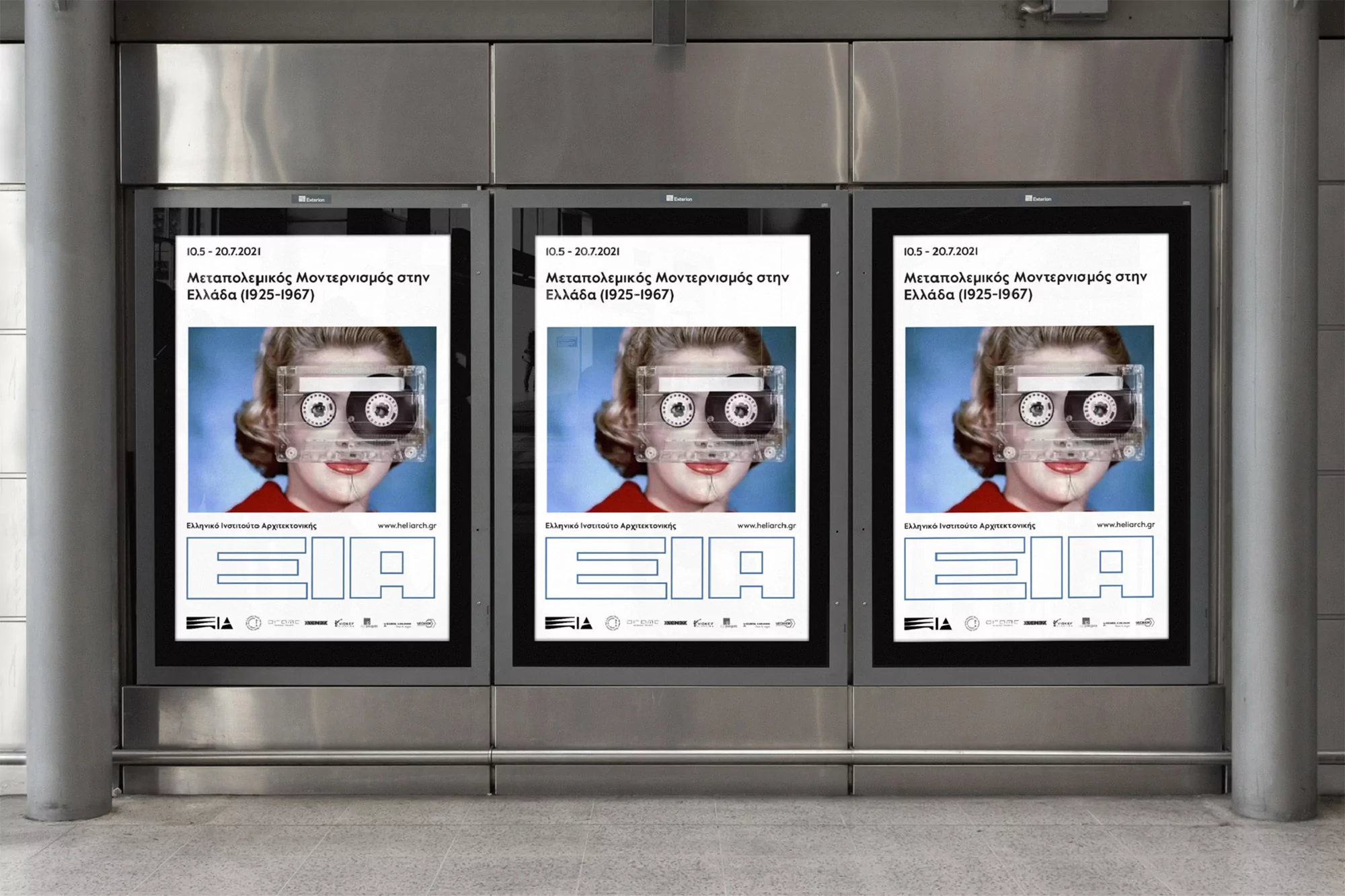 Three posters displayed indoors feature a woman with a cassette tape covering her eyes, promoting a modern art exhibition in Greece.