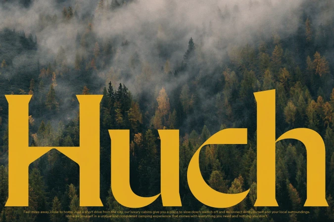 Landscape featuring a forest of evergreen trees, enveloped in fog, with golden typography 'Huch' overlaid in the foreground.