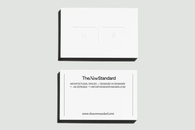 Two white business cards displayed on a pale grey background, featuring minimalist typography and clean debossed lettering.