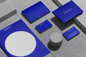 Blue stationery set with white typography and geometric circles arranged on a grey concrete surface