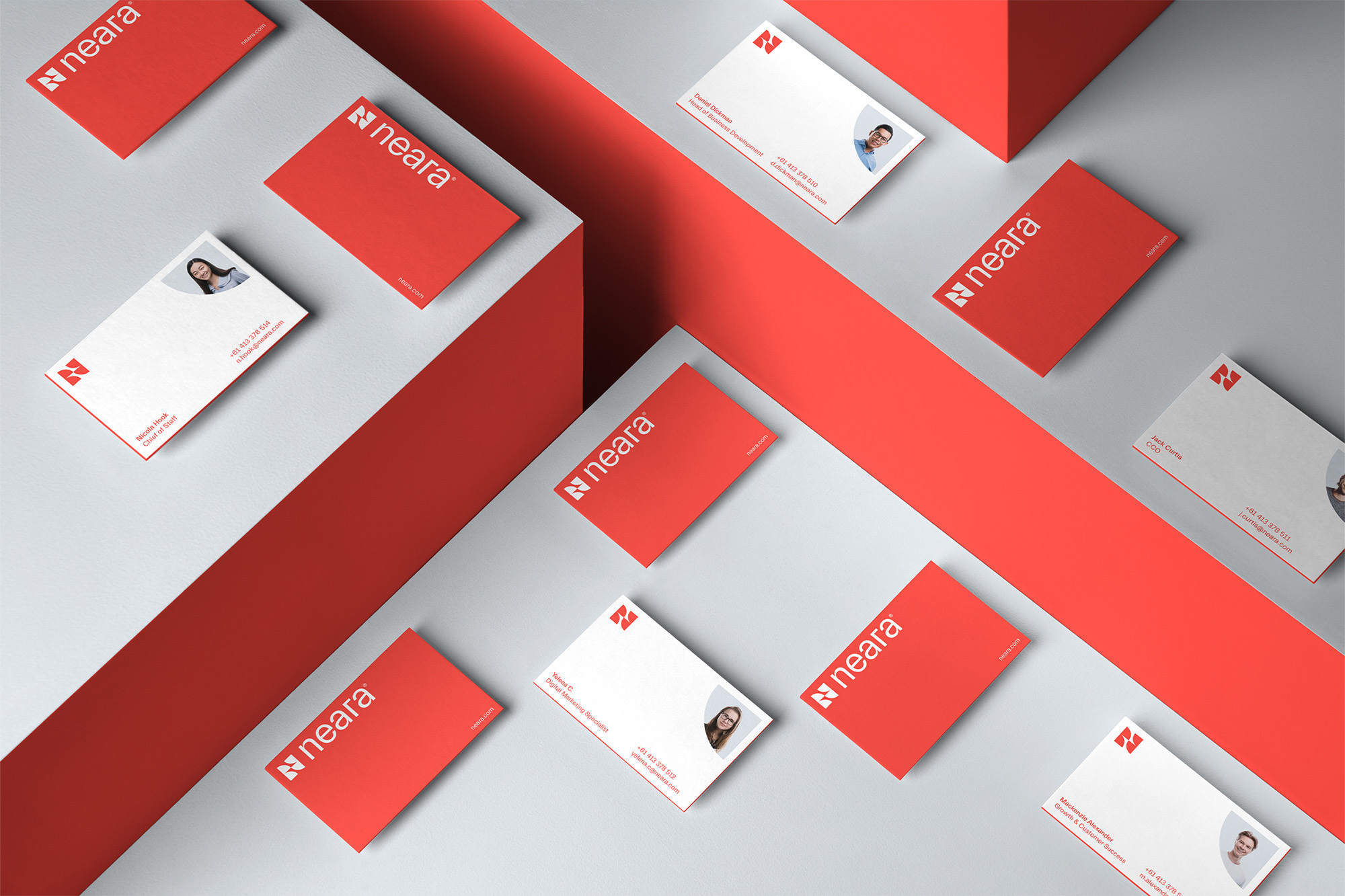Overhead view of multiple corporate business cards in red and white, arranged on a clean grey background, suggesting corporate branding.
