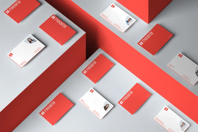 Overhead view of multiple corporate business cards in red and white, arranged on a clean grey background, suggesting corporate branding.