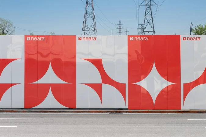 Red and white geometric wall art next to an empty street underneath a blue sky, with tall power lines in the background.