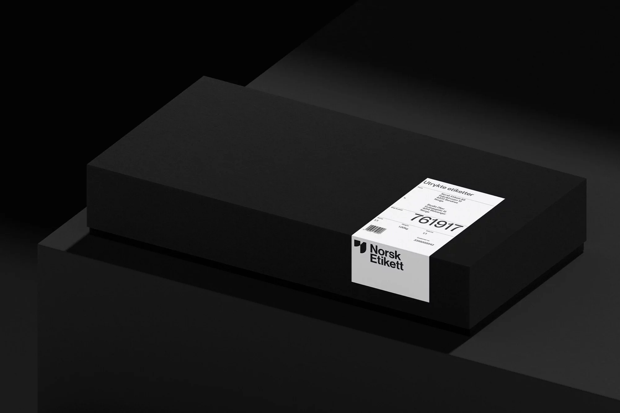 Black rectangular box with label on a dark geometric surface, creating a minimalist and modern product display. 