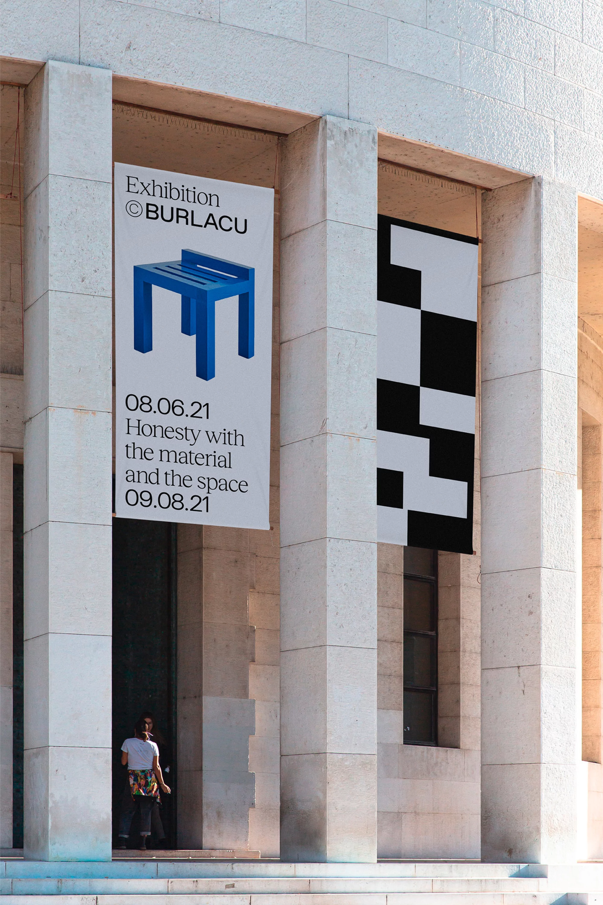 Architectural photo of a building facade with exhibition posters, featuring a person entering the building, under sunlight.
