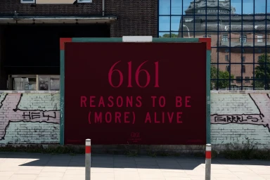 Large outdoor advertising billboard with burgundy background and pink typographic text reading 6161 reasons to be more alive by GIGI