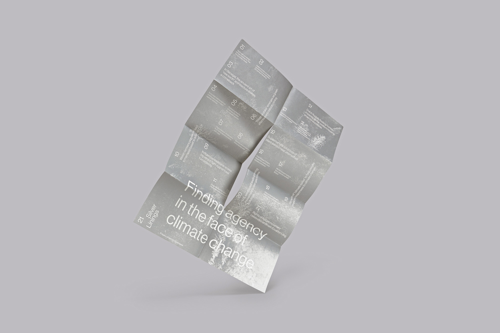 Abstract studio shot of a folded brochure in white with the text 'Finding agency in the face of climate change.' Light gray background.
